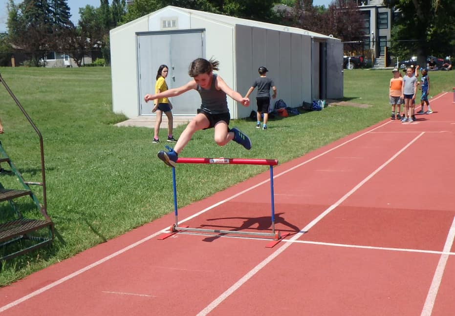 Kids doing a hurdles activity at a summer track and field day camp in Calgary.