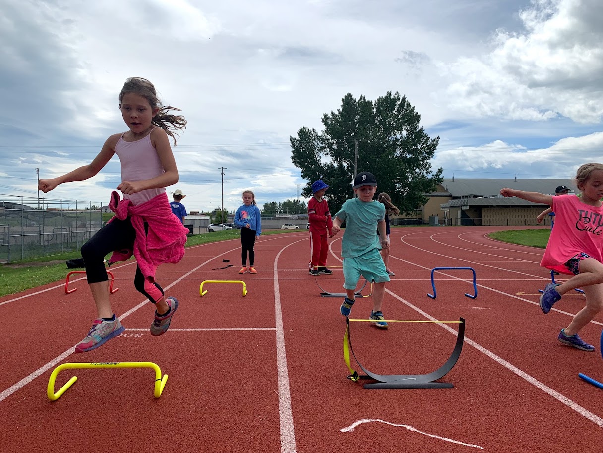 Kids doing a hurdles activity at a summer track and field day camp in Calgary.