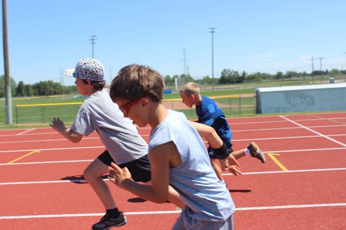 A child in Calgary at a summer camp for track and field races while sticking out his tongue.