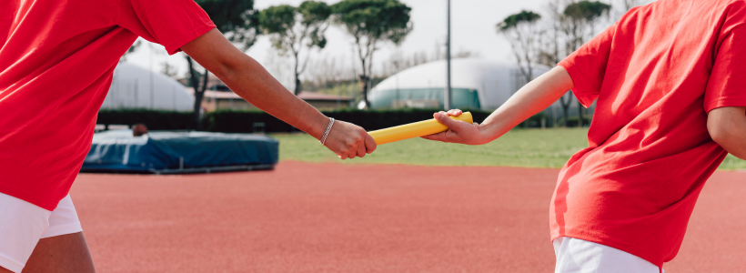 Two children hand a relay baton between hands in a track and field competition in Calgary.